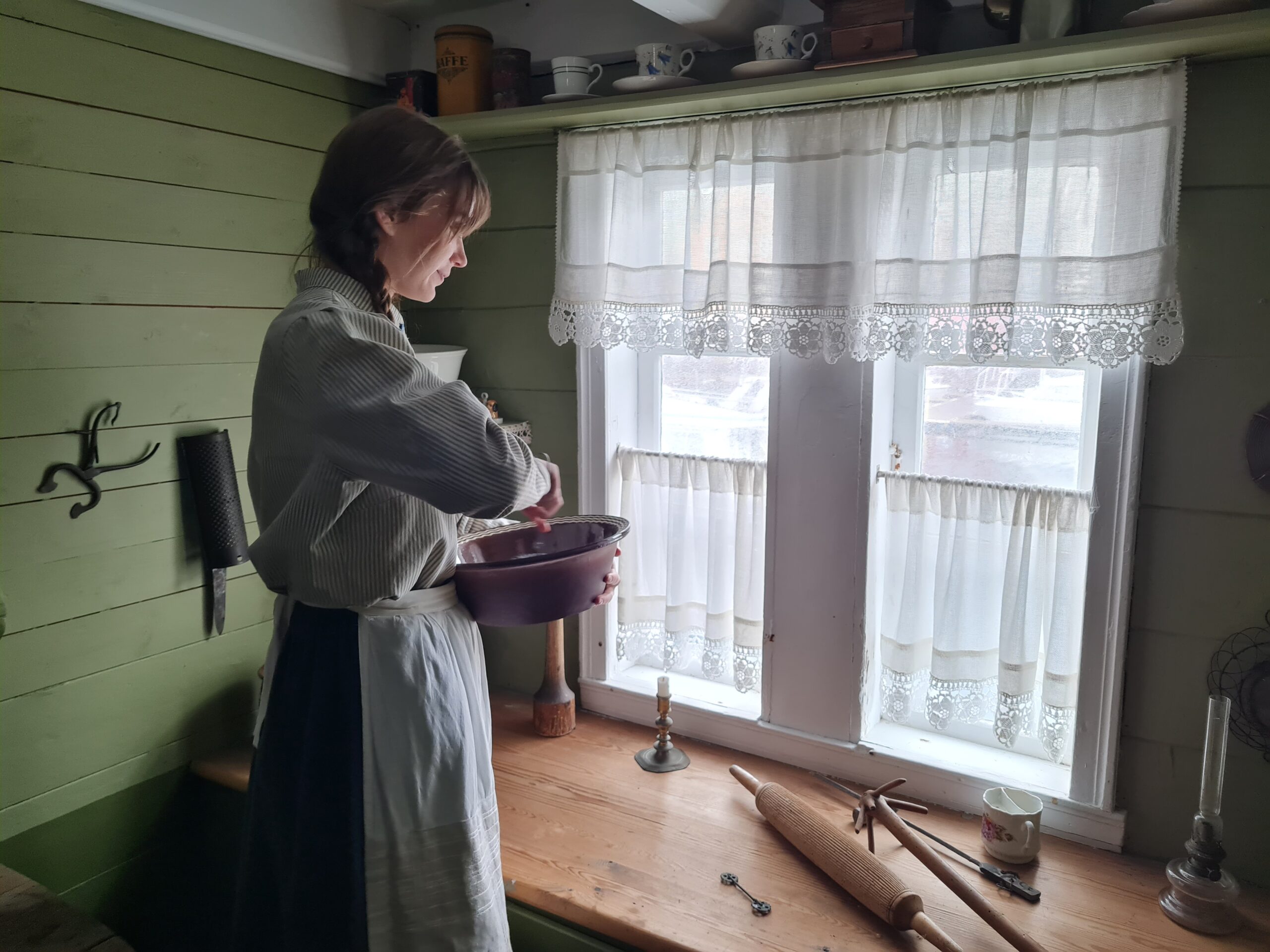 Tjenestejente som visper og ser ut vindu på et kjøkken